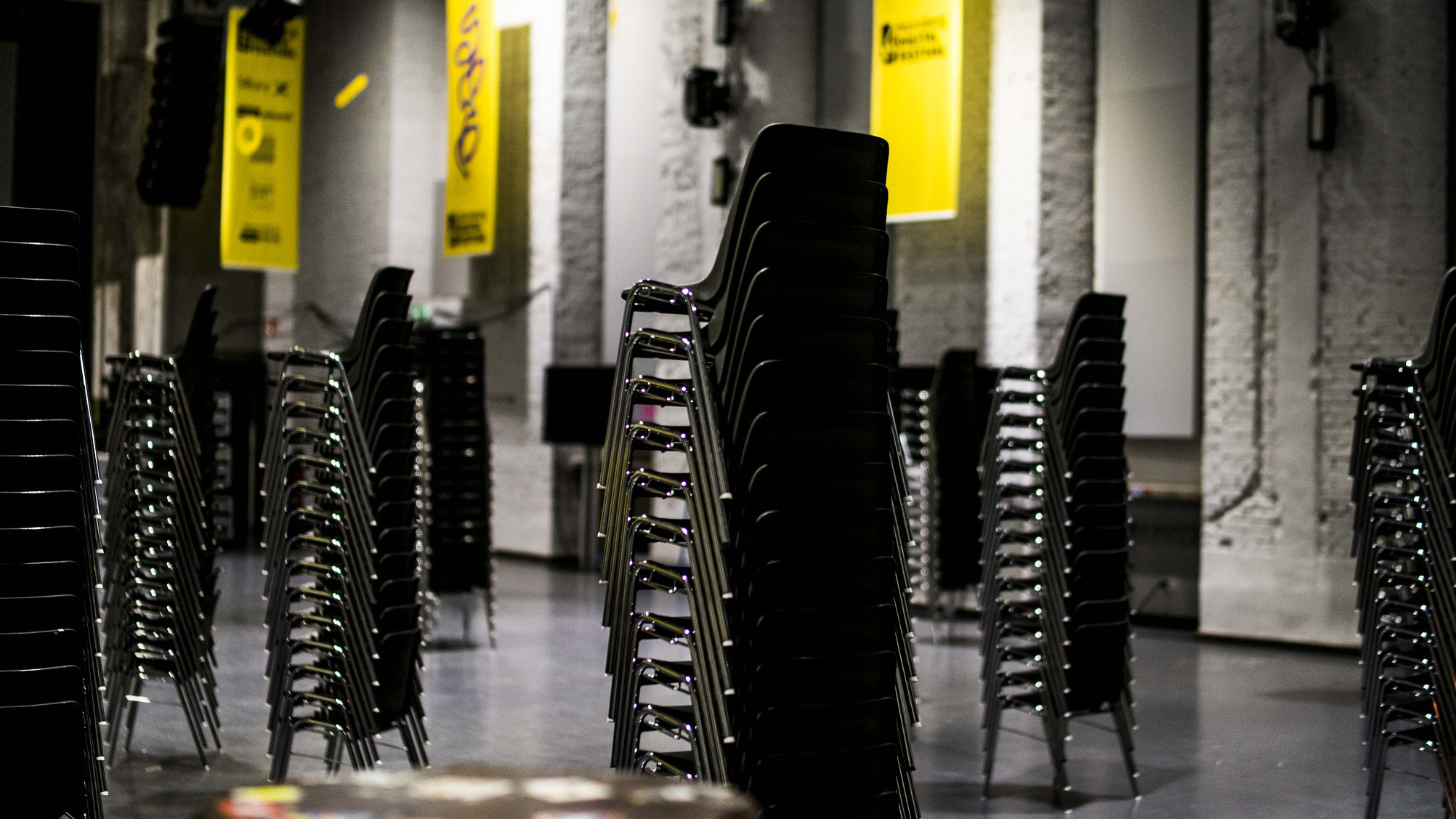 leere aufgestapelte Stühle in einer Halle, im Hintergrund Nürnberg Digital Festival Plakate