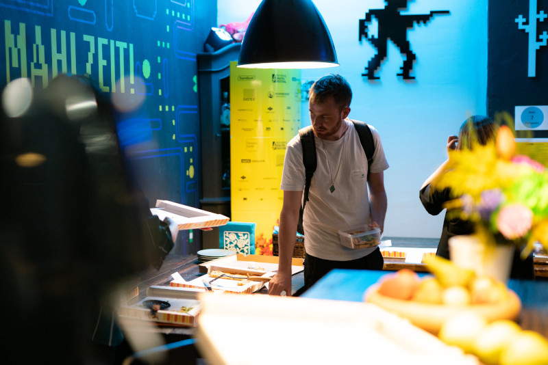 Mann steht in einem Raum vor einem Pizzabuffet, im Hintergrund Nürnberg Digital Deko