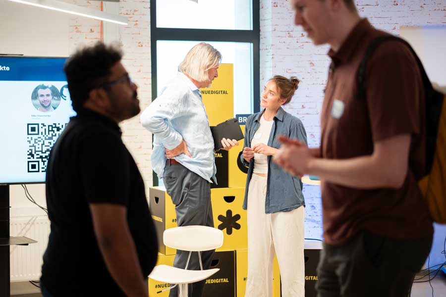 Vier Personen sitzen auf Bühne vor großer Leinwand mit farbigen Diagrammen und Begriffen wie „fear“ und „joyful“, Publikum im Vordergrund.