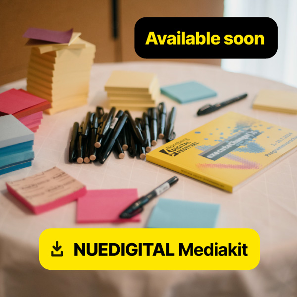 Lettering "NUEDIGITAL Mediakit". A table with pens, sticky notes, and festival brochures in the background.