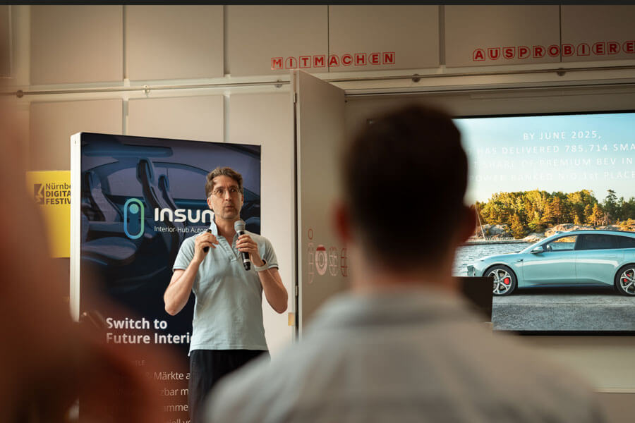 Mann spricht mit Mikrofon vor einem Display mit Auto und Text, Publikum sitzt im Vordergrund, Banner mit Nürnberg Digital Festival und „insun“ im Hintergrund.