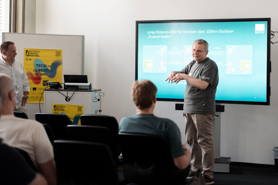 Mann steht vor Bildschirm und zeigt auf eine Grafik mit mehreren Bildausschnitten und Pfeilen, im Hintergrund Nürnberg Digital Festival Banner.