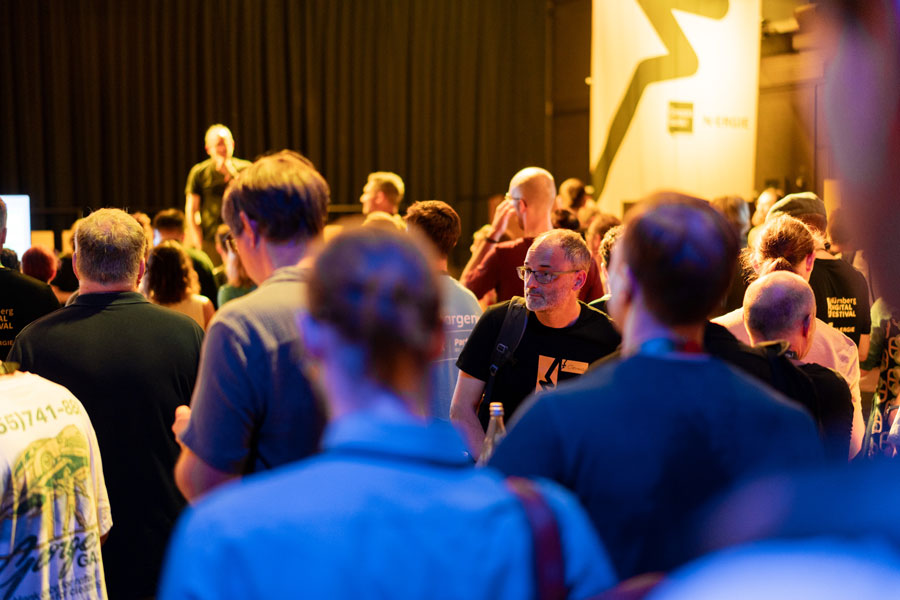 Menschenmenge blickt Richtung Bühne, im Hintergrund große gelbe Banner mit schwarzem Blitzsymbol.