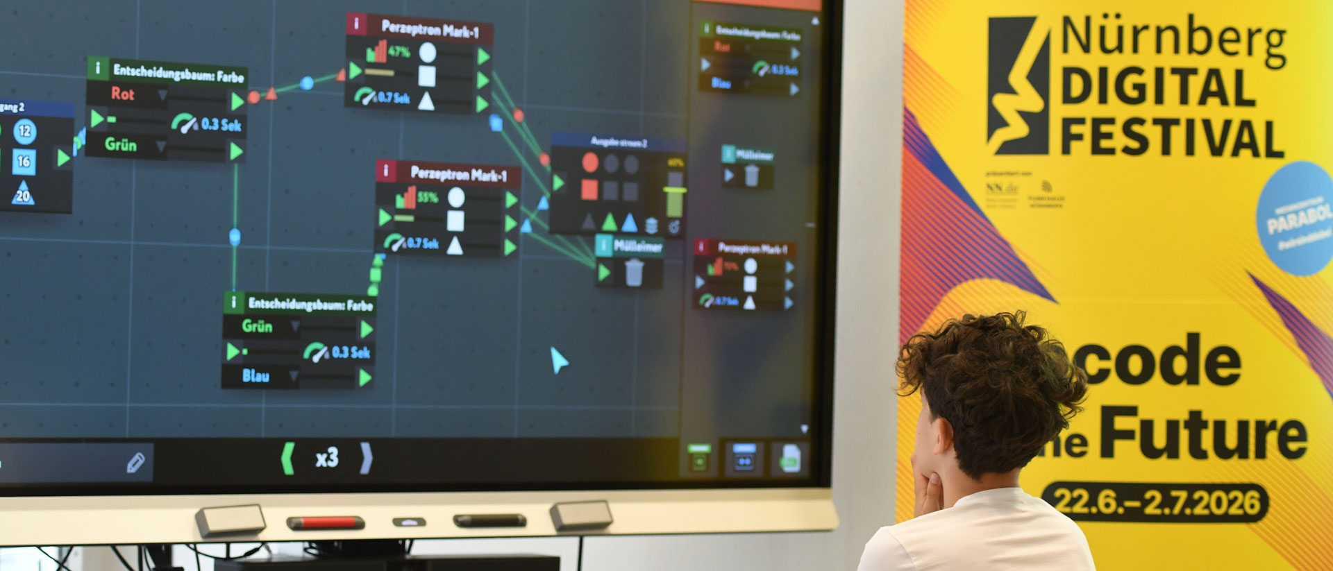 Person betrachtet ein Programmierdiagramm neben Banner „Nürnberg Digital Festival“.
