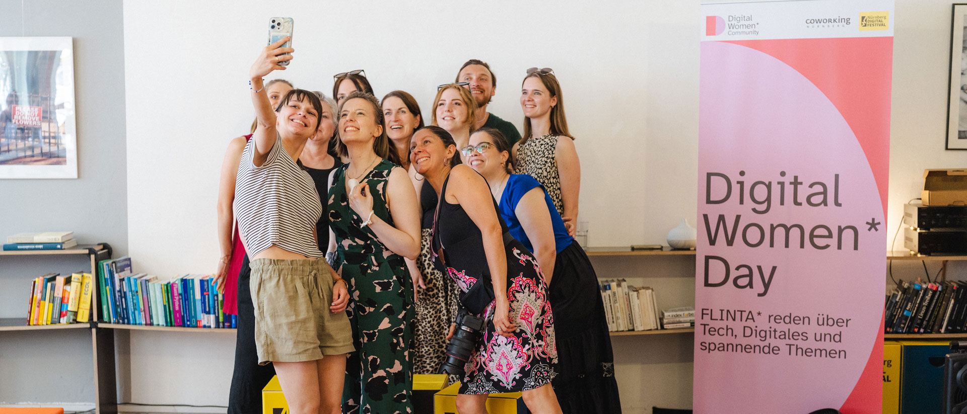 Gruppe macht ein Selfie neben Banner „Digital Women* Day“.